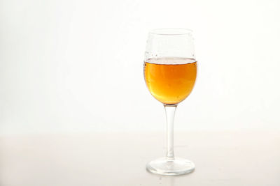 Close-up of wineglass on table against white background