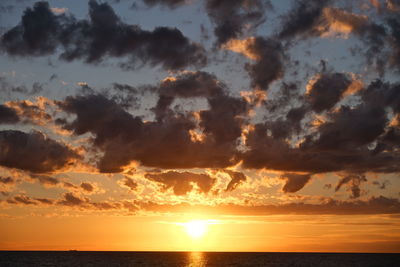 Scenic view of sea against dramatic sky during sunset