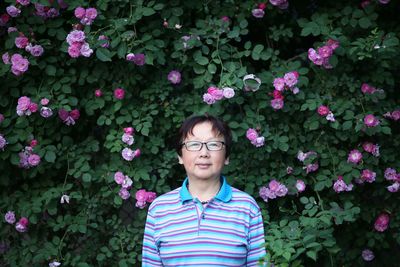 Portrait of woman standing by pink flowering plants