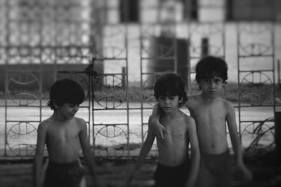 Waist up shot of three young brothers against metal railing