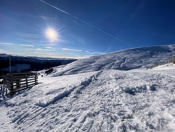 Snow covered landscape against blue sky