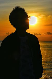 Man standing by sea against sky during sunset