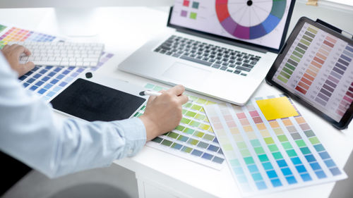 Cropped hands of businessman using laptop at office