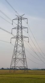 Low angle view of electricity pylon on field against sky