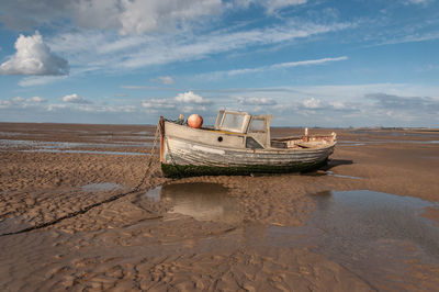 Boat moored on beach against sky
