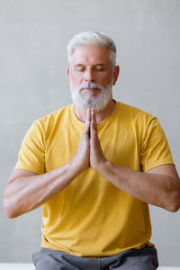 Portrait of young man drinking water against white background