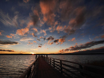 Pier over sea against sky during sunset