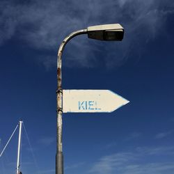 Low angle view of sign board against blue sky