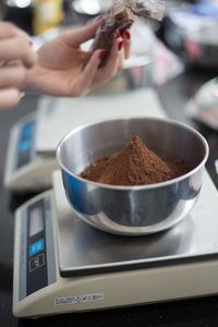 Cropped image of woman weighing coffee powder in store