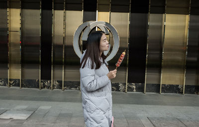 Full length of young woman standing against wall