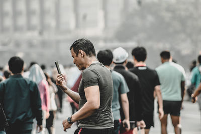 Man using mobile phone while standing in city