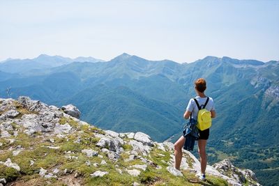 A woman looks at the landscape from the top of a mountain
