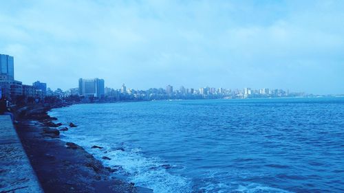 Scenic view of sea by buildings against sky