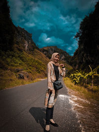 Young woman standing on road against mountain