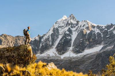 Low angle view of person standing on rock against sky