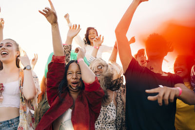 Multi-ethnic cheerful fans enjoying in music concert during sunny day