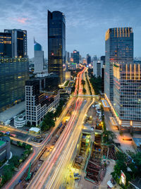 High angle view of light trails on road amidst buildings in city