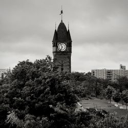 Clock tower amidst trees and buildings against sky