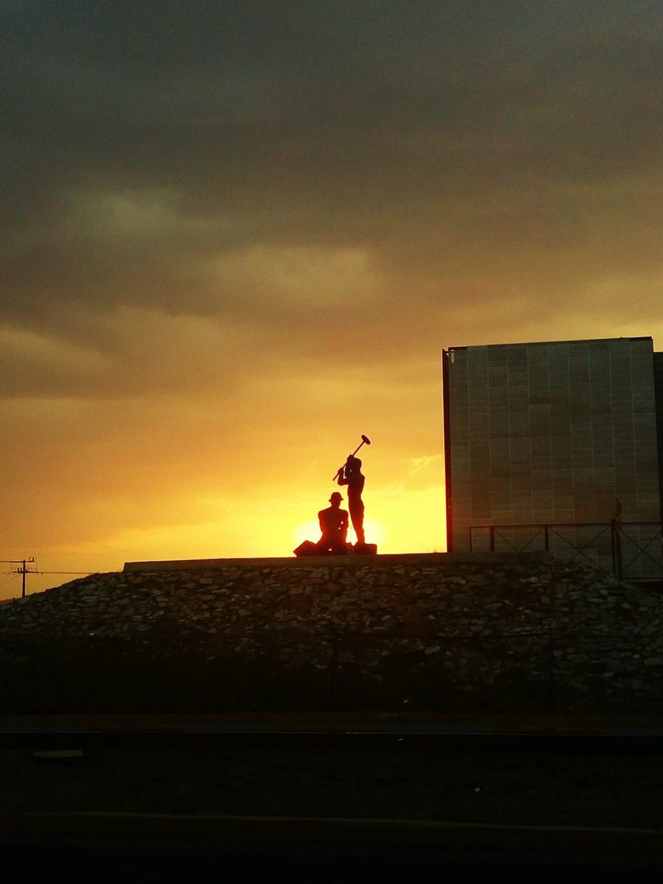 SILHOUETTE MAN STANDING ON BUILDING IN CITY AGAINST SKY