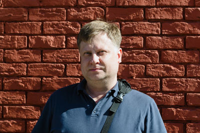 Portrait of man standing against brick wall
