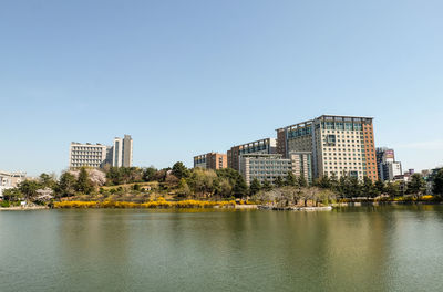 River by buildings in city against clear sky