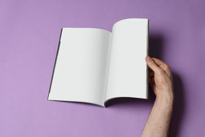 Midsection of person holding book against white background