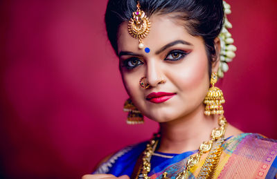 Portrait of beautiful young woman in traditional clothing standing against red background