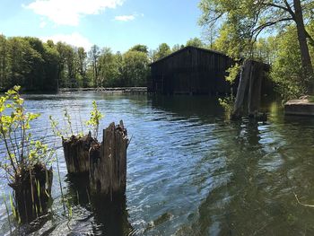 Wooden posts in lake against sky