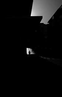 Silhouette person walking on road by buildings in city