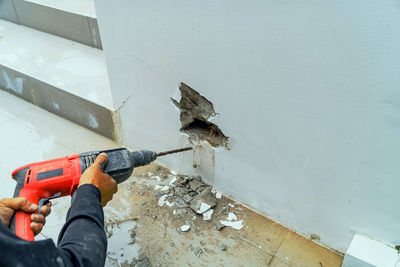 Male workers are using electric drill to drill the wall.