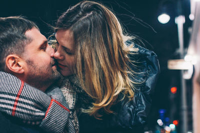 Couple kissing outdoors at night