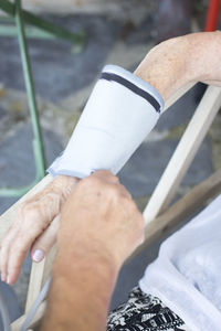 Cropped hands holding removing patient bandage from hand 