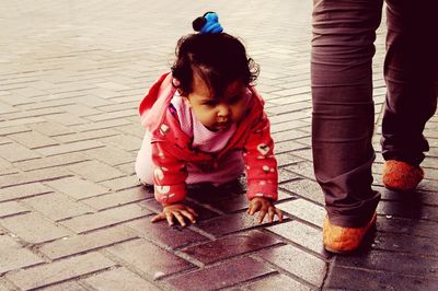 Cute baby girl crawling on footpath