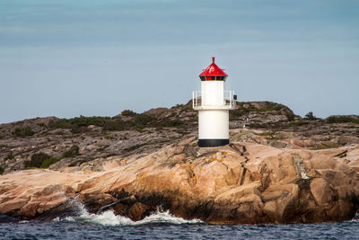 Lighthouse on rock formations against sky