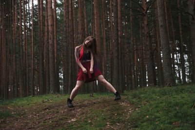 Young woman standing against trees in forest