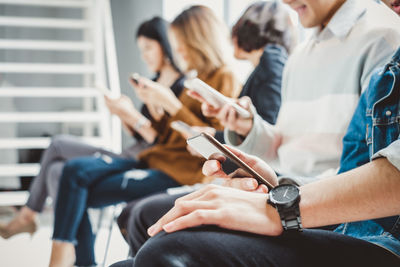 People using smart phone while sitting in row