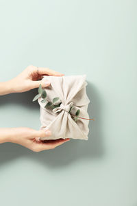 Cropped hand of woman holding gift against pink background