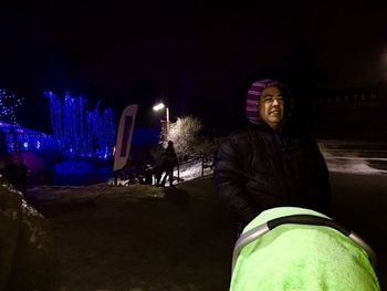 Portrait of smiling woman standing in illuminated park at night