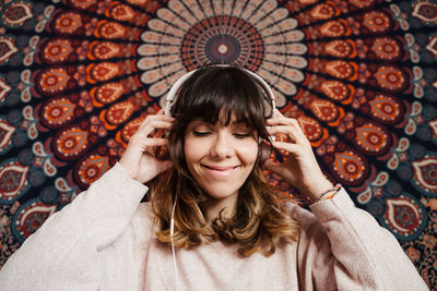 Close-up of woman wearing headphones against abstract backgrounds