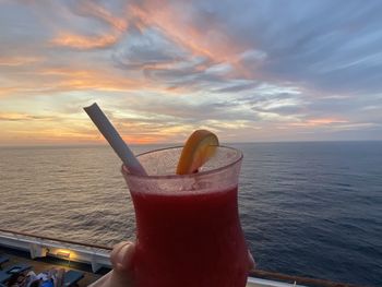 Close-up of drink on beach against sunset