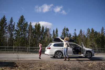 Mother and daughter jumping next to car