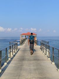 Rear view of woman on pier over sea against sky