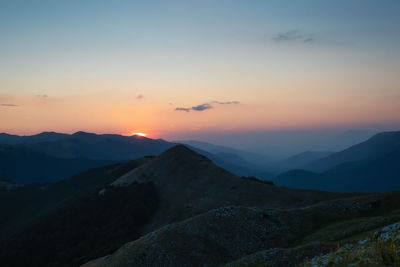 Scenic view of silhouette mountains against sky during sunset