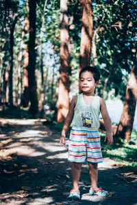 Full length of girl standing by tree in forest