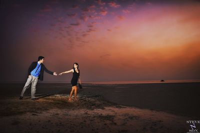 People on beach against sky during sunset