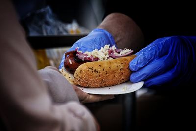 Cropped hands of male vendor giving hot dog to customer