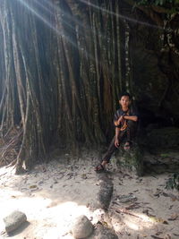 Portrait of young man sitting against trees in forest