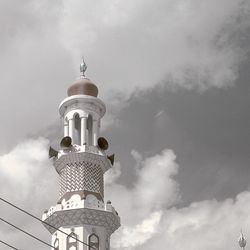 Low angle view of minaret against cloudy sky