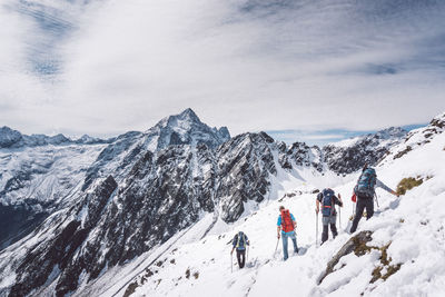 Hikers on snowcapped mountains against sky 