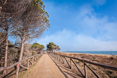 Walkway by sea against sky